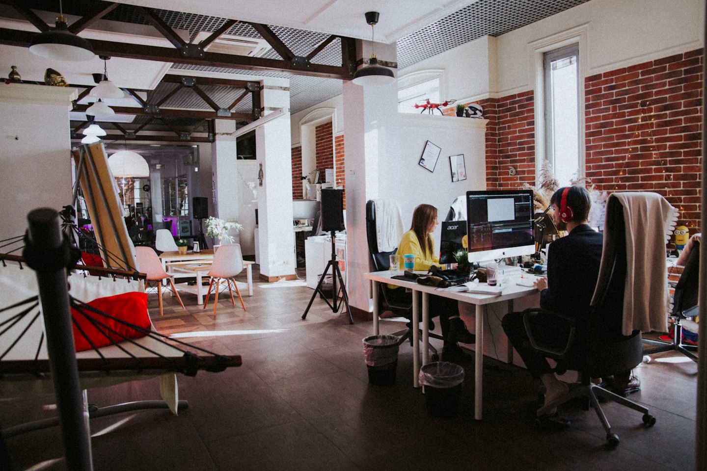 Dua profesional bekerja di komputer di kantor open-plan yang terang.